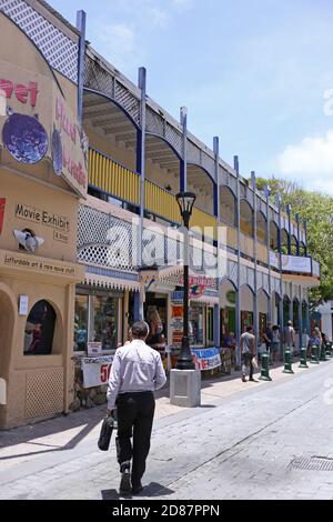 Un homme d'affaires est en marche dans les rues de St Martin, entouré de touristes et d'architecture colorée. Banque D'Images