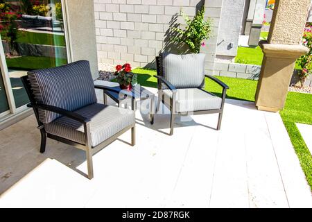 Patio arrière couvert avec petite table en métal et deux chaises Avec coussins à rayures Banque D'Images