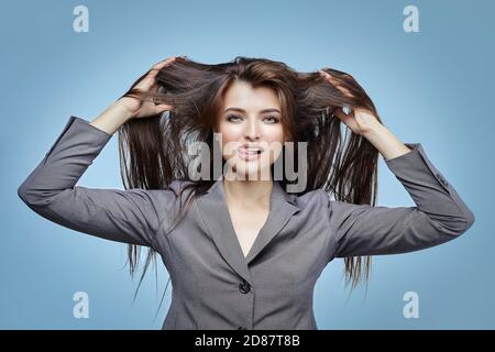 Belle fille plaise en jeu devant l'appareil photo. Gros plan portrait dans le Studio sur un fond bleu Banque D'Images