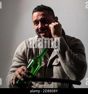 Homme ivre qui boit du vin. Un gars déprimé avec de l'alcool de bouteille, triste et malheureux. Banque D'Images