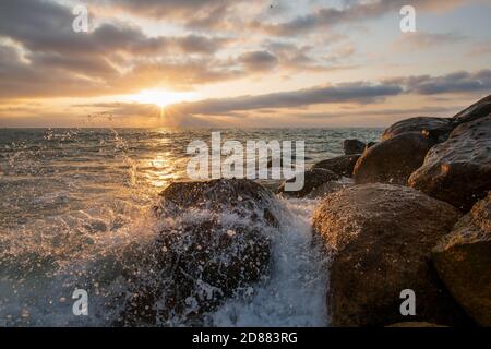 Une vague océanique au coucher du soleil se brise sur la mer avec le soleil sur l'horizon océanique Banque D'Images