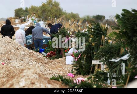 Ciudad Juarez, MEXIQUE. 27 octobre 2020. Les employés du cimetière enterrent les corps de personnes infectées par le COVID-19 à Ciudad Juarez, une colonne de fumée s'élève du crématoire du cimetière municipal de San Rafael. Les victimes de la COVID-19 sont enterrées dans une partie distincte du cimetière. Aujourd'hui, le Mexique a atteint un total de 900,000 cas et près de 90,000 décès dus à la COVID-19. Crédit : Corrie Boudreaux/Alay Live News Banque D'Images