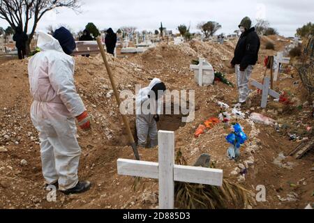 Ciudad Juarez, MEXIQUE. 27 octobre 2020. Les employés du cimetière enterrent les corps de personnes infectées par le COVID-19 à Ciudad Juarez, une colonne de fumée s'élève du crématoire du cimetière municipal de San Rafael. Les victimes de la COVID-19 sont enterrées dans une partie distincte du cimetière. Aujourd'hui, le Mexique a atteint un total de 900,000 cas et près de 90,000 décès dus à la COVID-19. Crédit : Corrie Boudreaux/Alay Live News Banque D'Images