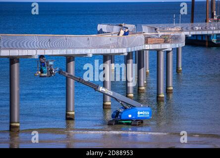 Koserow, Allemagne. 22 octobre 2020. Les ouvriers de la construction travaillent à partir d'une plateforme élévatrice sur la nouvelle jetée sur la plage de l'île d'Usedom. La jetée doit s'étendre sur environ 280 mètres dans la mer, mais sa forme incurvée sera différente de celle des jetées précédentes sur la mer Baltique. Selon les plans, les caractéristiques spéciales sont, en plus d'une apparence vague dans la vue en plan, une tête de pont presque carrée avec un clocher. La construction est financée par des fonds de l'UE. Credit: Jens Büttner/dpa-Zentralbild/dpa/Alay Live News Banque D'Images