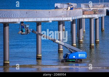 Koserow, Allemagne. 22 octobre 2020. Les ouvriers de la construction travaillent à partir d'une plateforme élévatrice sur la nouvelle jetée sur la plage de l'île d'Usedom. La jetée doit s'étendre sur environ 280 mètres dans la mer, mais sa forme incurvée sera différente de celle des jetées précédentes sur la mer Baltique. Selon les plans, les caractéristiques spéciales sont, en plus d'une apparence vague dans la vue en plan, une tête de pont presque carrée avec un clocher. La construction est financée par des fonds de l'UE. Credit: Jens Büttner/dpa-Zentralbild/dpa/Alay Live News Banque D'Images