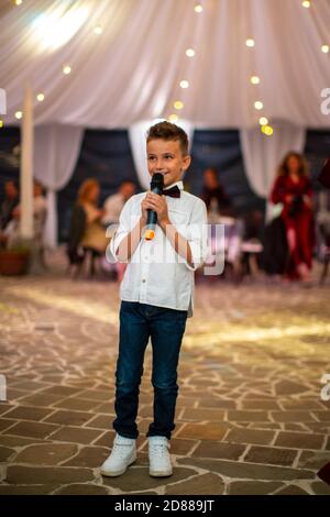 Mignon petit garçon avec le microphone chant pour les invités à la vacances Banque D'Images