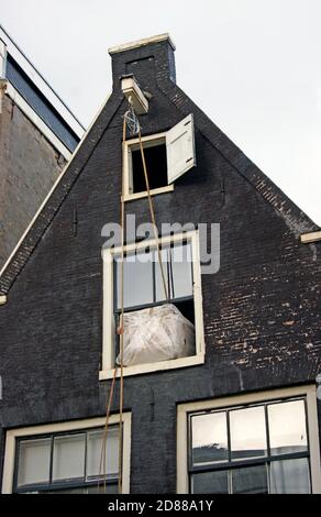 Une série de photos montre le levage de meubles à l'étage supérieur d'une maison de canal à Amsterdam, Hollande où le système de levage de poulie extérieure est utilisé. Banque D'Images