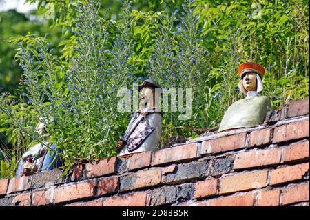 Des bustes sculptés de Burghers médiévaux du XVe siècle par Dariusz Przewiezlikowski bordent un mur de briques dans la vieille ville de Torun, en Pologne. Banque D'Images