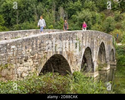 Les pèlerins sur le pont médiéval en pierre sur la rivière Ulzama - Trinidad de Arre, Navarre, Espagne Banque D'Images