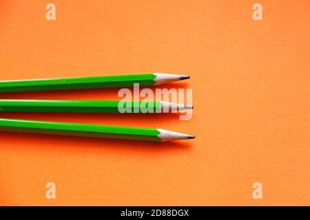 trois crayons verts sur fond orange Banque D'Images