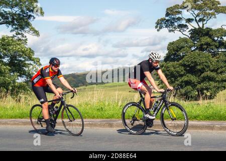 Deux cyclistes mâles à cheval Boardman sports Road bike sur la route de campagne traversant le pont d'autoroute dans la campagne du Lancashire, Royaume-Uni Banque D'Images