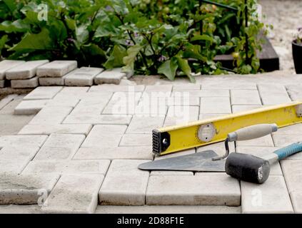 Le maître pose les pavés en couches. Pavage de chemins de briques de jardin. Pose de dalles de béton dans la cour de la maison sur une base de sable Banque D'Images