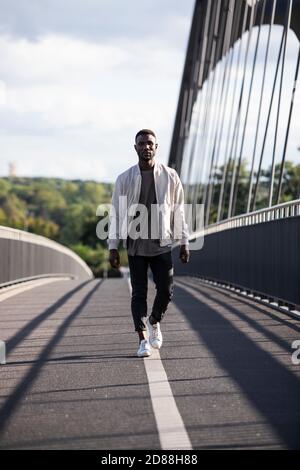 Un jeune homme noir confiant se dirige vers l'appareil photo en toute confiance. Longueur totale. Verticale. Banque D'Images