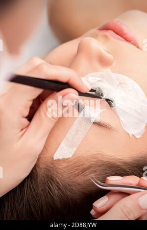 Jeune femme caucasienne recevant des extensions de cils procédure dans le salon de beauté Banque D'Images