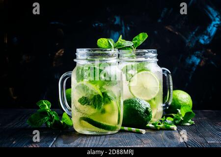 Thé vert glacé à la chaux et à la menthe dans des pots en verre, fond sombre, mise au point sélective Banque D'Images