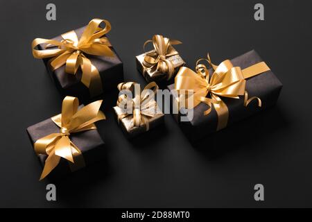 Boîtes-cadeaux dorées emballées de façon festive sur fond noir. Vue isométrique. Concept des fêtes et du Vendredi fou Banque D'Images