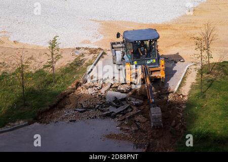 Russie, Kaluga - 27 OCTOBRE 2020 : tracteur brisant l'ancien asphalte avec un godet avant la construction d'une nouvelle route. Banque D'Images