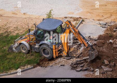 Russie, Kaluga - 27 OCTOBRE 2020 : tracteur brisant l'ancien asphalte avec un godet avant la construction d'une nouvelle route. Banque D'Images