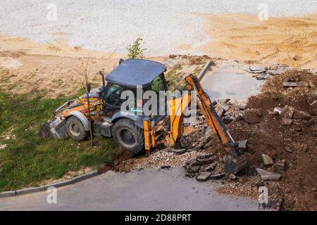 Russie, Kaluga - 27 OCTOBRE 2020 : tracteur brisant l'ancien asphalte avec un godet avant la construction d'une nouvelle route. Banque D'Images