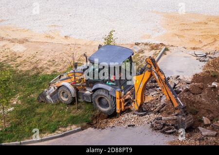 Russie, Kaluga - 27 OCTOBRE 2020 : tracteur brisant l'ancien asphalte avec un godet avant la construction d'une nouvelle route. Banque D'Images