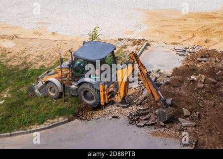 Russie, Kaluga - 27 OCTOBRE 2020 : tracteur brisant l'ancien asphalte avec un godet avant la construction d'une nouvelle route. Banque D'Images