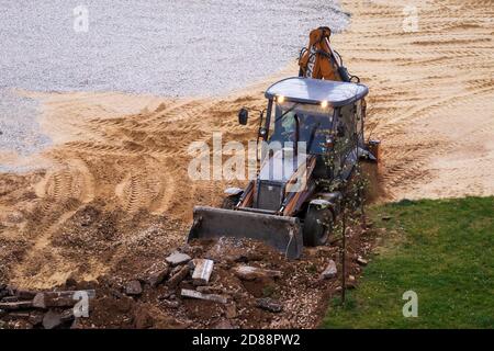 Russie, Kaluga - 27 OCTOBRE 2020 : tracteur brisant l'ancien asphalte avec un godet avant la construction d'une nouvelle route. Banque D'Images