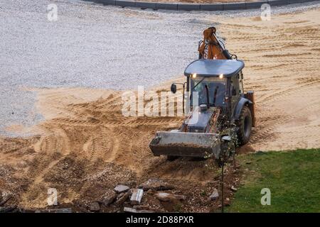 Russie, Kaluga - 27 OCTOBRE 2020 : tracteur brisant l'ancien asphalte avec un godet avant la construction d'une nouvelle route. Banque D'Images