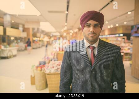 Jeune homme d'affaires sikh indien élégant portant le turban tout en explorant le ville Banque D'Images