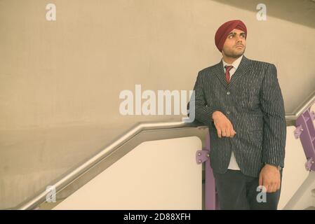Jeune homme d'affaires sikh indien élégant portant le turban tout en explorant le ville Banque D'Images