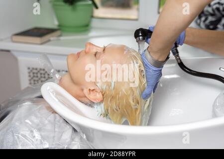 Hands washing off hair dye. Beauty salon client. Stock Photo