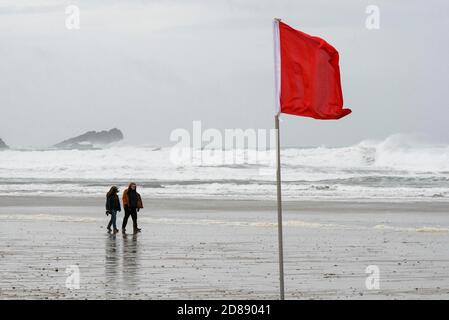 Newquay, Cornwall, Royaume-Uni. 28 octobre 2020. Météo Royaume-Uni. Un couple a du mal à marcher dans les vents violents sur la plage de Fistral comme de grandes vagues des restes de l'ouragan Epsilon crash à Newquay dans les Cornouailles pendant la mi-période des vacances scolaires. Crédit photo : Graham Hunt/Alamy Live News Banque D'Images