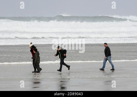 Newquay, Cornwall, Royaume-Uni. 28 octobre 2020. Météo Royaume-Uni. Une famille lutte pour marcher dans les vents violents sur la plage de Fistral comme de grandes vagues des restes de l'ouragan Epsilon crash à Newquay dans les Cornouailles pendant la mi-période des vacances scolaires. Crédit photo : Graham Hunt/Alamy Live News Banque D'Images