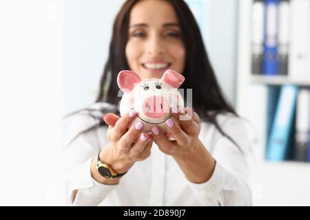 Jeune belle femme tenant une banque de porc sous forme de cochon en mains gros plan Banque D'Images