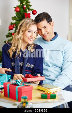 Joyeux couple souriant tout en emballant des cadeaux pour Noël Banque D'Images