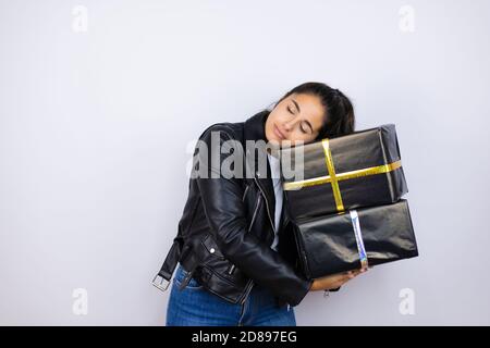 Jeune belle femme tenant des cadeaux sur fond blanc isolé dormir et fatigué de son cadeau Banque D'Images
