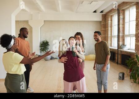 Groupe de jeunes heureux se saluant mutuellement embrassant et parler en studio de danse Banque D'Images