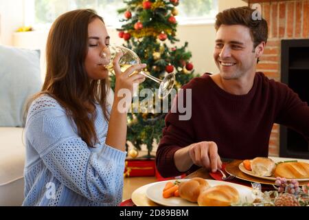 Un jeune couple dînant ensemble à noël Banque D'Images