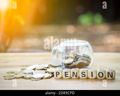 Pièces en pot avec bloc de bois écrit TEXTE DE PENSION sur table de bois pour économiser de l'argent pour la retraite financière et l'assurance de pension. Concept pour Banque D'Images