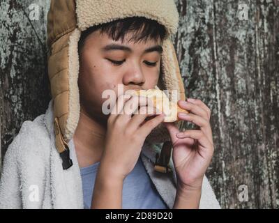 Enfant affamé mangeant du pain qui demande de l'aide pour le don de nourriture de la part des gens dans la rue à la ville. Enfant sans abri non identifié mendiant dans la rue. Elle Banque D'Images