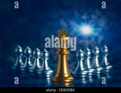 Le roi d'or d'échecs est entouré de tomber autour des pièces d'échecs d'argent à la lutte avec le travail d'équipe à la victoire, le concept de stratégie d'affaires et de leader et Banque D'Images