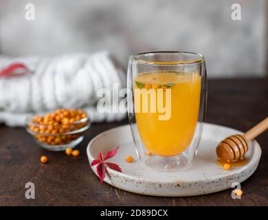 Thé chaud à l'argousier avec menthe et miel. Thé à base de vitamines à base de plantes. fond en bois, gros plan Banque D'Images