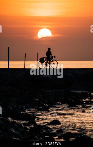 Silhouette d'un cycliste debout au lever du soleil sur le front de mer, Fuengirola, Malaga, Espagne Banque D'Images