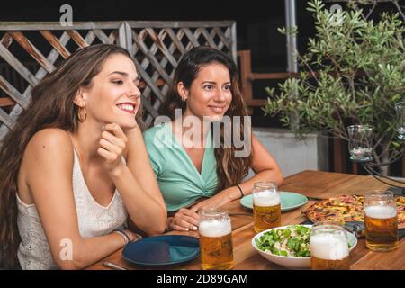 De beaux amis rient et applaudissent avec des bières et manger de la pizza. Groupe de personnes boire et manger concept Banque D'Images