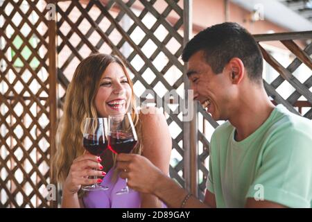 Un moment heureux avec un couple de course mixte qui se fait boire du vin et rire. Concept de boisson de couple Banque D'Images