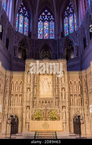 Des vitraux colorés à l'extrémité est de la nef de la cathédrale nationale de Washington encadrent l'autel haut finement sculpté ci-dessous. Banque D'Images