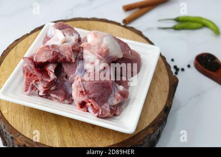 Viande de chèvre ou morceaux de mouton ou d'agneau frais et crus. Préparation du curry de mouton indien. Épice à l'arrière-plan comme des bâtons de cannelle, poudre de piment rouge, Banque D'Images