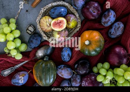 Fruits et légumes frais sur une table. Vue de dessus photo de raisins, citrouilles, prunes et figues. Arrière-plan texturé gris. L'automne encore la vie. Banque D'Images