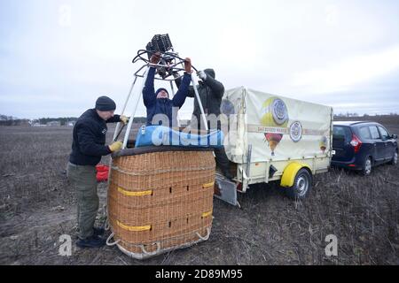 Préparatifs pour le vol en montgolfière : les hommes plaçant le brûleur à gaz sur le dessus du panier, de la voiture et de la remorque avec l'équipement installé sur un arrière-plan Banque D'Images