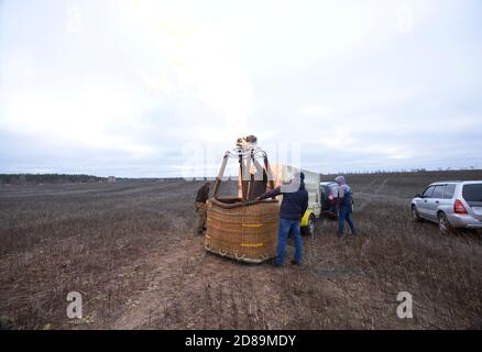 Préparatifs pour le vol en montgolfière : les hommes plaçant le brûleur à gaz sur le dessus du panier, de la voiture et de la remorque avec l'équipement Banque D'Images