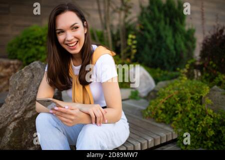 une jeune femme indépendante communique avec les clients au téléphone pendant que dans un parc verdoyant Banque D'Images